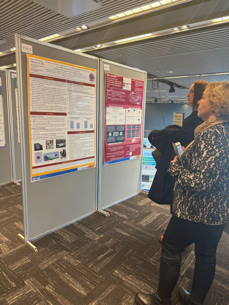 Conference attendees in front of poster presenting the work of the Office of Community Outreach and Engagement at the Eurogin conference in Stockholm, Sweden